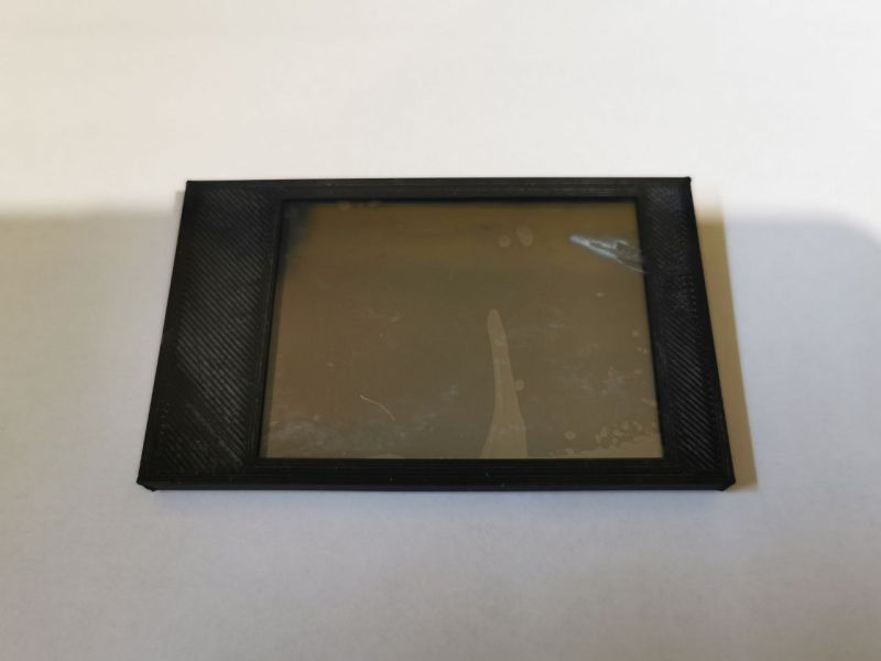 Black rectangular plastic bezel with an inserted display on a light background