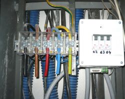 Skrzynka elektryczna z przewodami kolorowymi i wyłącznikiem nadprądowym.