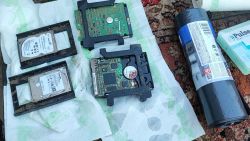 Damaged hard drives lying on a surface covered with paper towels.