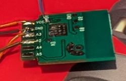 Close-up of a green PCB with labeled pins and attached wires.
