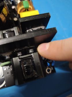 Zbliżenie na sekcję zasilacza DeepCool, palec wskazuje na element przy radiatorze