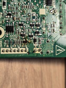 Zbliżenie na płytkę drukowaną z uszkodzonymi elementami elektronicznymi.