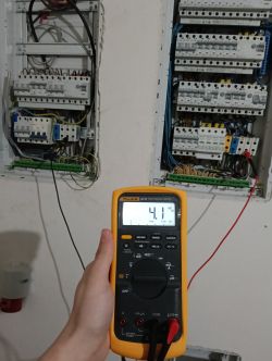 Multimetr cyfrowy pokazujący pomiar napięcia w rozdzielnicy elektrycznej