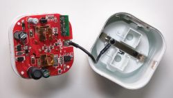 Red PCB with relays and electronic components inside a smart plug housing.