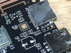 Zbliżenie na płytkę PCB z widocznymi złączami microSD, USB i wyprowadzeniami UART opisanymi jako GND, TX, RX.