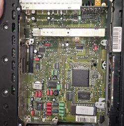 Wnętrze radia samochodowego: płytka PCB z układami scalonymi, kondensatorami i ekranami metalowymi