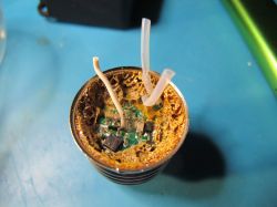 Damaged internal electronic component of an LED spotlight with visible corrosion and wires.