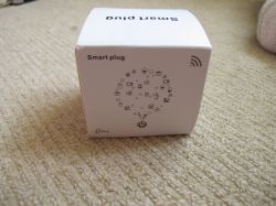 Smart Plug Box Box containing a smart plug lying on a carpet.