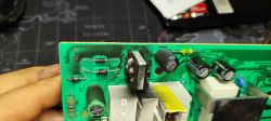 Zniszczona płytka drukowana z osadzoną sadzą wokół elementów elektronicznych.