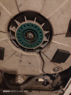 Zbliżenie na tylną część bębna pralki Electrolux z widoczną zieloną nakładką serwisową i centralną śrubą mocującą.