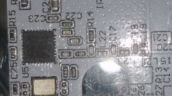 Macro photo of a PCB with an IC and markings R15, C25, U5, plus a bright glare on a round metallic area