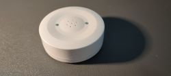 Tuya Water Leak Sensor Close-up of a white, circular Tuya water leak sensor on a dark surface.