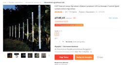Zestaw 8 solarnych lamp ogrodowych z białym światłem LED zamontowanych w rzędzie na tle krzewów.