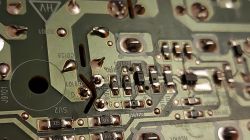 Close-up of a printed circuit board with electronic components, including capacitors and copper traces.