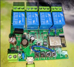 Close-up of a circuit board with an ESP8266 module and four blue relays.