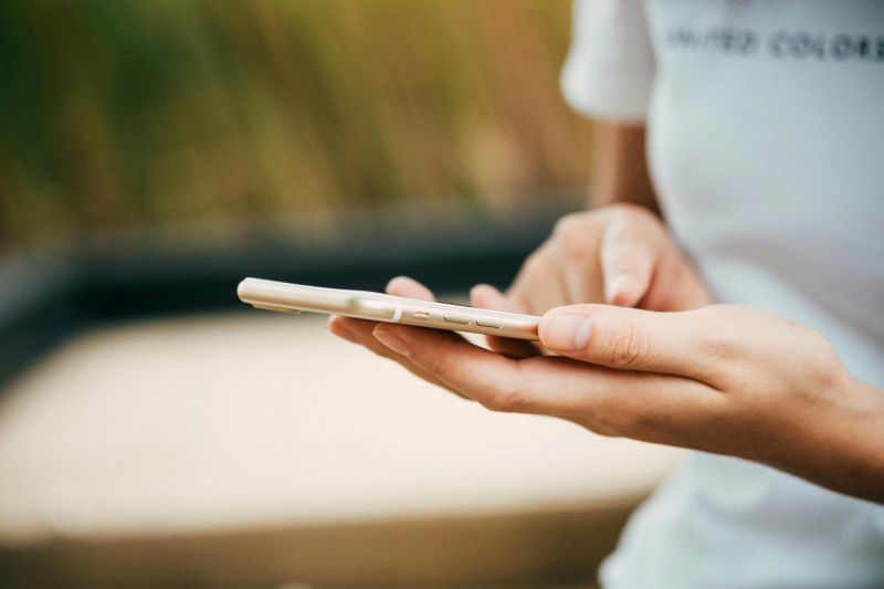 Osoba trzymająca złoty smartfon i używająca go jedną ręką