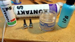 Dwa potencjometry na blacie obok środków Kontakt PR, Kontakt S, damping grease i butelki IPA