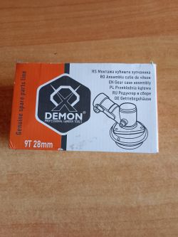 Pudełko „DEMON” z opisem 9T 28 mm i rysunkiem przekładni kątowej na drewnianym blacie