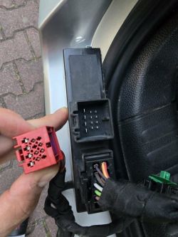 Roter Mehrfachstecker neben schwarzer Modulbuchse und eingestecktem Kabelstecker im Auto