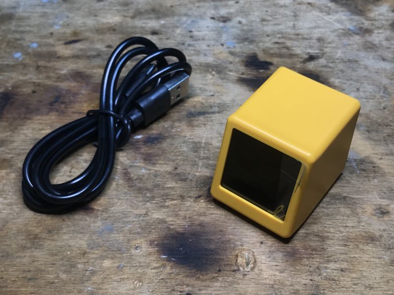 Kompaktes SmallTV-Ultra-Gerät mit USB-C-Kabel Kleines gelbes Gerät mit Display und schwarzem USB-C-Kabel auf einer Holzoberfläche.
