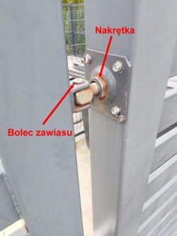 Zbliżenie na zawias metalowej bramy z oznaczoną nakrętką i bolcem zawiasu