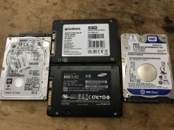 Cztery dyski twarde: dwa SSD i dwa HDD na drewnianym tle.