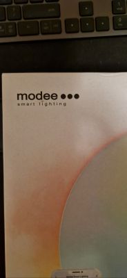 Opakowanie lampy Modee Smart Lighting leżące na klawiaturze.