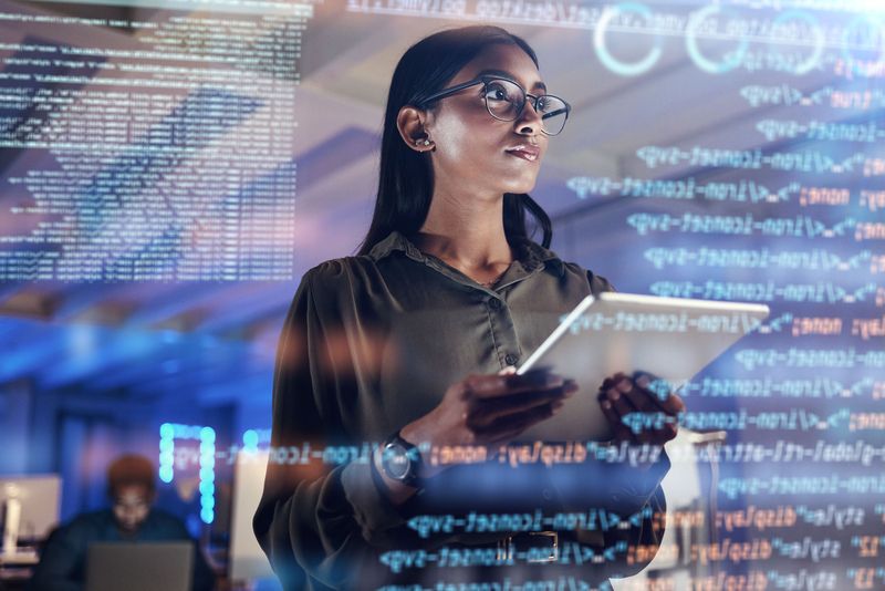 Kobieta z tabletem patrzy na ekran z kodem w biurze informatycznym