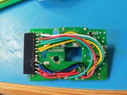 Printed circuit board with soldered colorful wires on a blue surface.