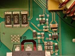 Zbliżenie uszkodzonej płytki PCB z zaznaczonymi rezystorami R015 i elementami SMD