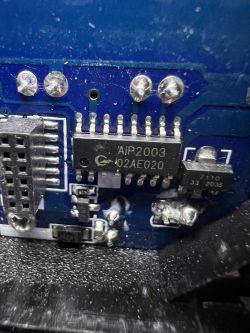 Close-up of an electronic board with a visible chip marked AiP2003.