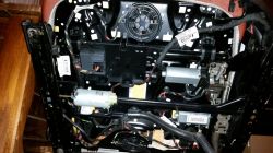 Spód fotela samochodowego z widocznymi elementami elektronicznymi i wiatrakiem.