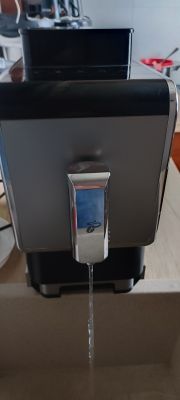 Przód automatycznego ekspresu do kawy, z wylewki wypływa strumień wody do zlewu.