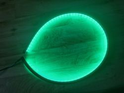 Green LED strip in an arc shape on a wooden floor.