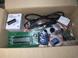 Cardboard box containing various electronic components, including a PCB board, relays, and a power plug.