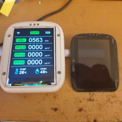 Two air quality measurement devices and an LCD casing on a wooden desk