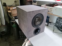 Subwoofer z płyty MDF ze szarym fornirem na stoliku w warsztacie.