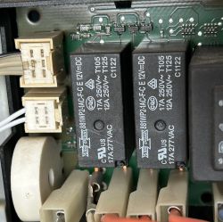 Zbliżenie na płytkę PCB z dwoma czarnymi przekaźnikami 12V DC i białymi złączami