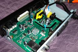 Wnętrze tunera z widocznymi elementami elektronicznymi, w tym kondensatorami i innymi podzespołami.