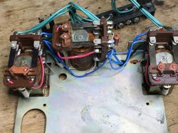 Three electromagnetic relays on a metal plate, wired with blue and green leads.