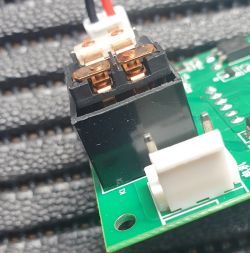 Zbliżenie na układ elektroniczny z przekaźnikiem na zielonej płytce PCB.