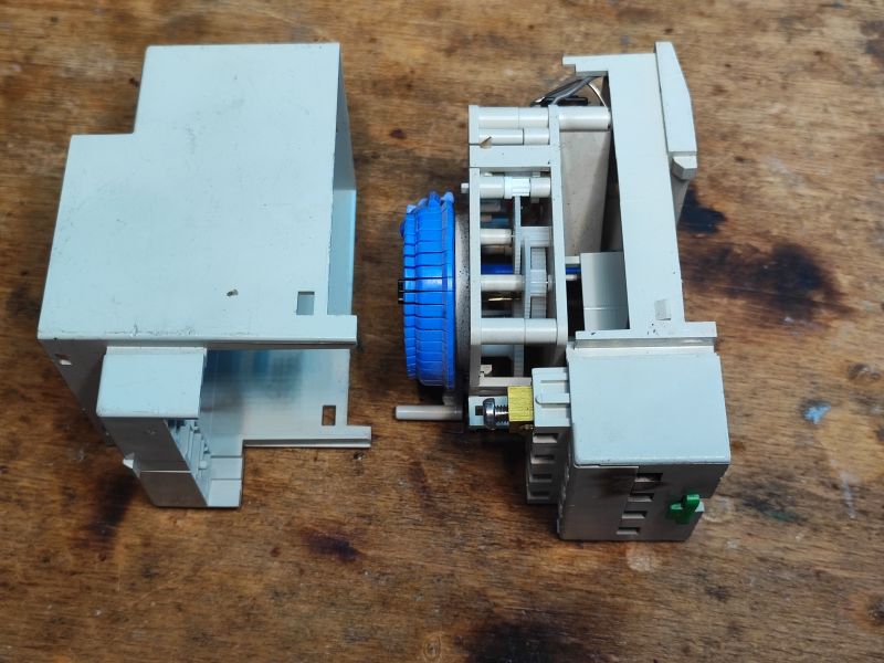 Wnętrze mechanicznego programatora czasowego z osiami i zębatkami.