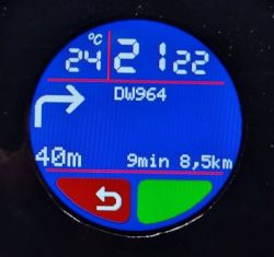 Okrągły ekran urządzenia z nawigacją: 21:22, 24°C, strzałka skrętu, 40 m, 9 min, 8,5 km