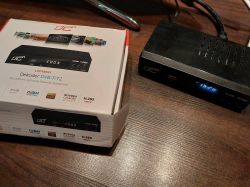 Dekoder DVB-T2 na stole obok oryginalnego opakowania.