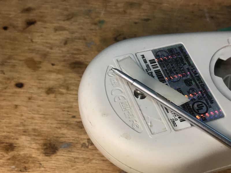 Bottom of an Old PS/2 Mouse with Screw Photo of the bottom of an old PS/2 computer mouse with a screw for opening the case.