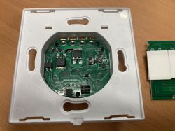 Interior of a white electronic panel with a visible green printed circuit board and electronic components.