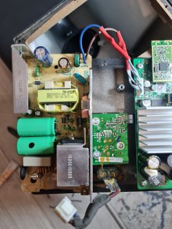Image of an opened power supply case showing electronic components, capacitors, and wire connections.