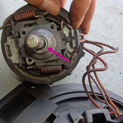 Zbliżenie na wnętrze silnika elektrycznego z tulejką wskazaną strzałką.