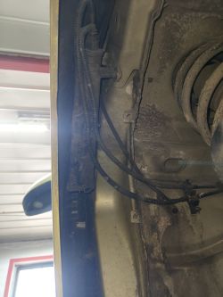 Pochłaniacz oparów zamontowany przy nadkolu Citroëna C4 Grand Picasso, widoczne przewody i sprężyna zawieszenia.
