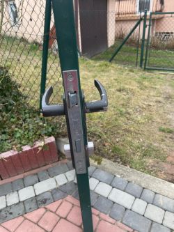 Zamek w drzwiach ogrodzeniowych z dwiema klamkami w kształcie litery L